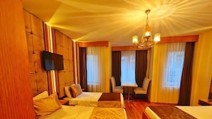 A hotel room with two beds, a small table, chairs, a TV, and a chandelier. - Cetinkaya Suites (Istanbul)