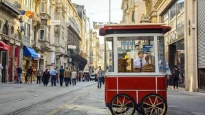 A red and white trolley on a street with pedestrians and buildings in the background. - Cetinkaya Suites (Istanbul)