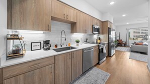 A modern kitchen with wooden cabinets, stainless steel appliances, and a white countertop. - King Bed & Rooftop Views Prime Bankers Hill near Balboa Park (San Diego)