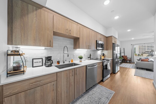 Una cocina moderna con armarios de madera, electrodomésticos de acero inoxidable y encimera blanca.