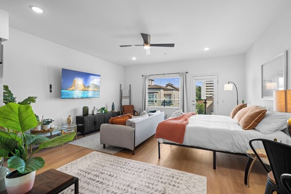 Un dormitorio moderno con cama, sofá, escritorio y un amplio ventanal.