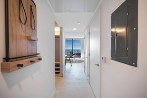 Un pasillo moderno con un mueble de madera, una puerta con cerradura de seguridad y vistas a un balcón con sillas.
