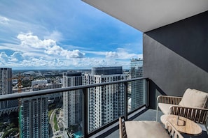 Un balcón con vistas a un paisaje urbano, incluyendo edificios altos y grúas de construcción.