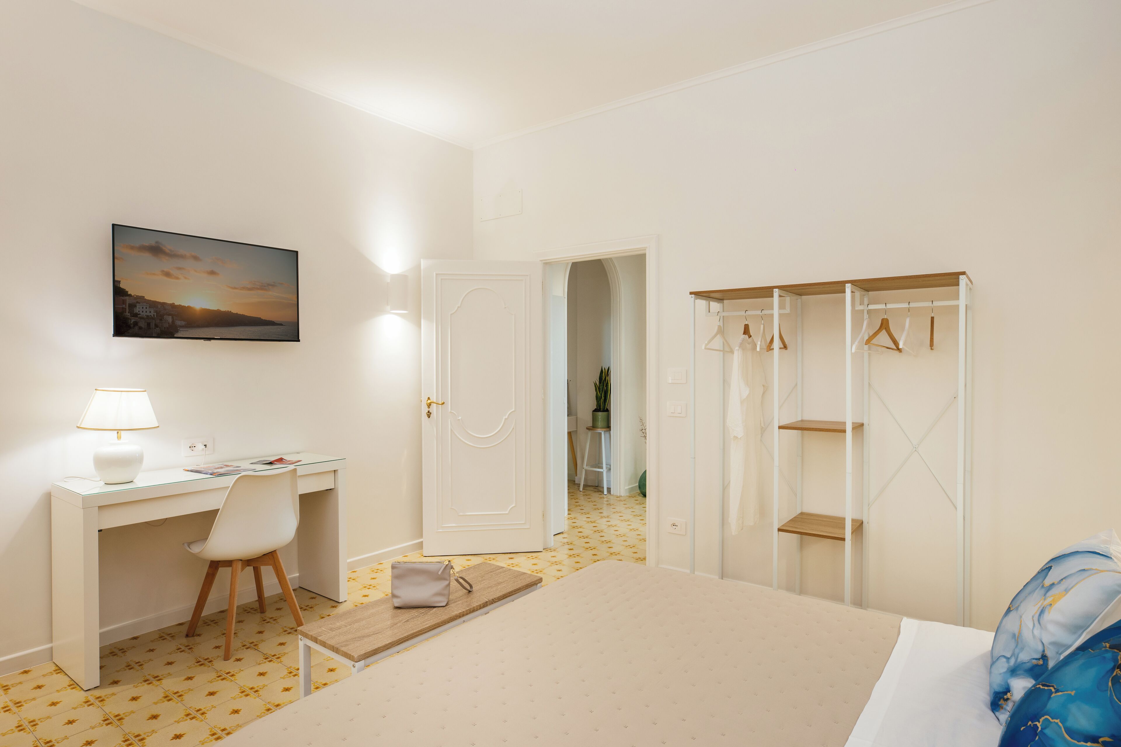 Ein Hotelzimmer mit Bett, Schreibtisch mit Stuhl, Kleiderschrank und einem Bild an der Wand.