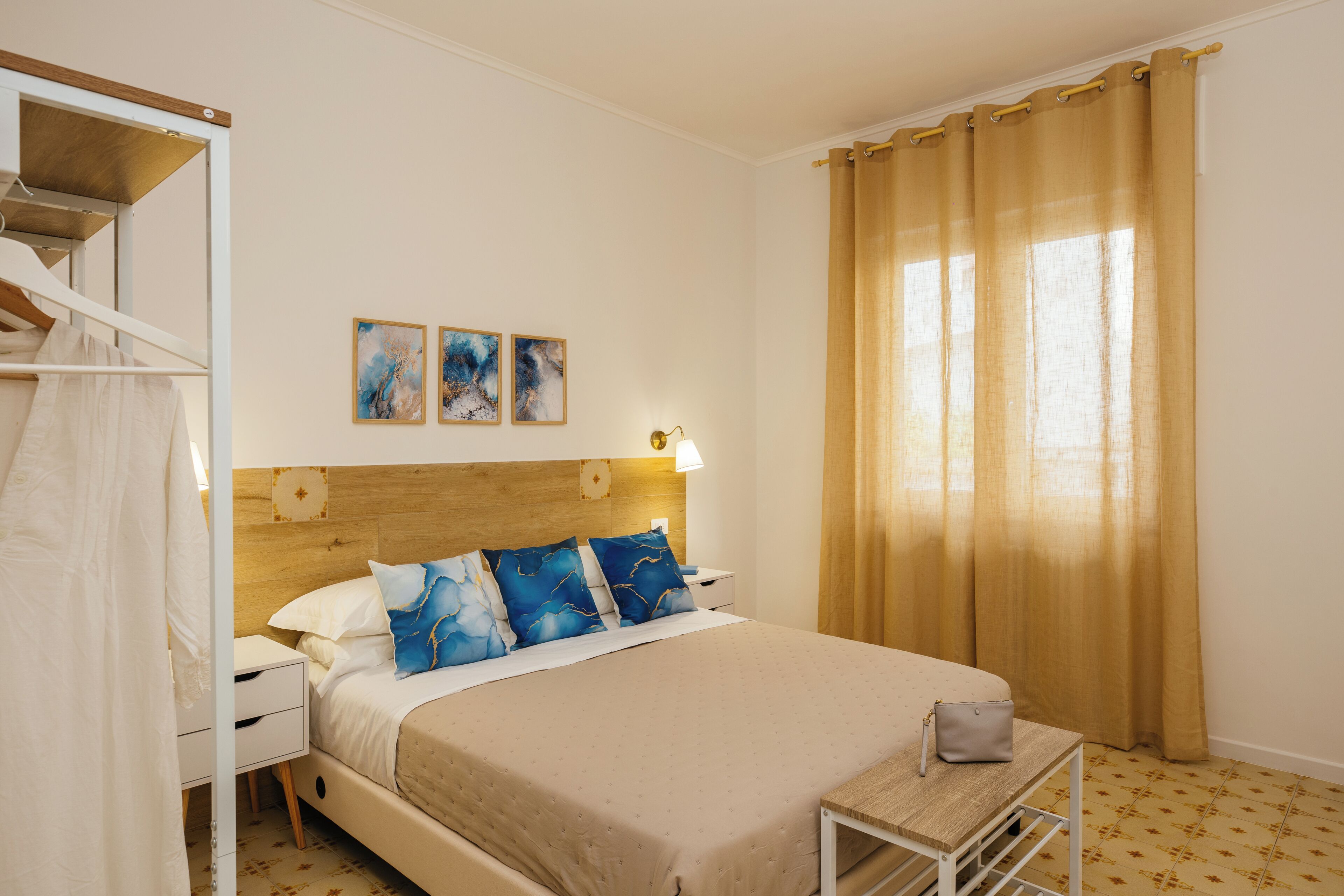 A neatly arranged hotel room with a bed, bedside table, and a small table with a bag.