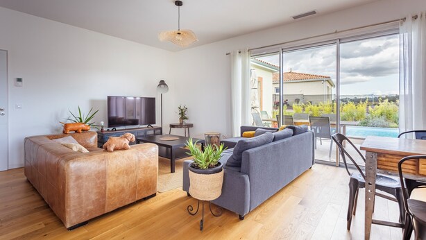 A modern living room with a sofa, TV, and a dining area with a table and chairs. - Modern country house - sleeps 8/10 - heated pool (Tarabel)