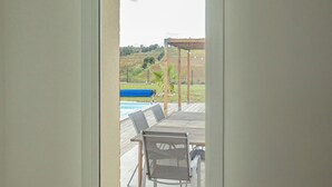 A view through a door to an outdoor patio with a pool, chairs, and a pergola. - Modern country house - sleeps 8/10 - heated pool (Tarabel)
