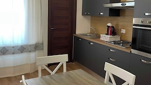 A modern kitchen with dark cabinets, a wooden dining table, and pendant lights. - Vacation Home Balai Porto Torres (Porto Torres)