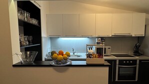 Eine moderne Küche mit weißen Schränken, einer schwarzen Arbeitsplatte, einem Spülbecken, einer Mikrowelle und einer Kaffeemaschine.