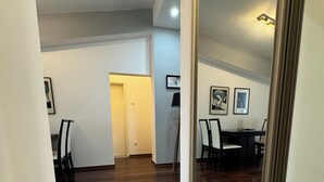 Ein geräumiger Raum mit Holzboden, einem Essbereich mit Stühlen und einem Tisch sowie einer Tür zu einem anderen Zimmer.