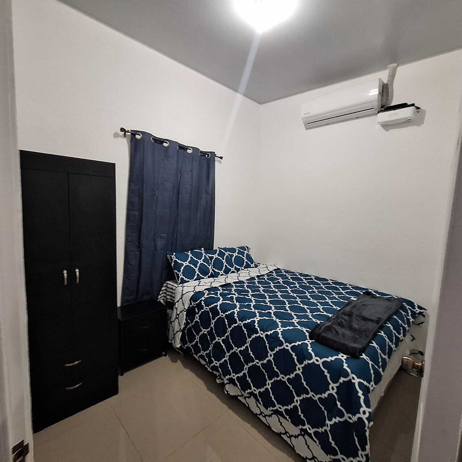 A bedroom with a bed, a wardrobe, and a ceiling fan.