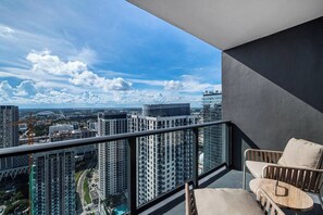 Uma varanda com vista para um horizonte urbano, incluindo edifícios altos e guindastes de construção.