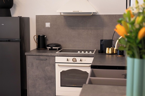 Fully equipped kitchen with fridge, oven, stovetop, and kettle.