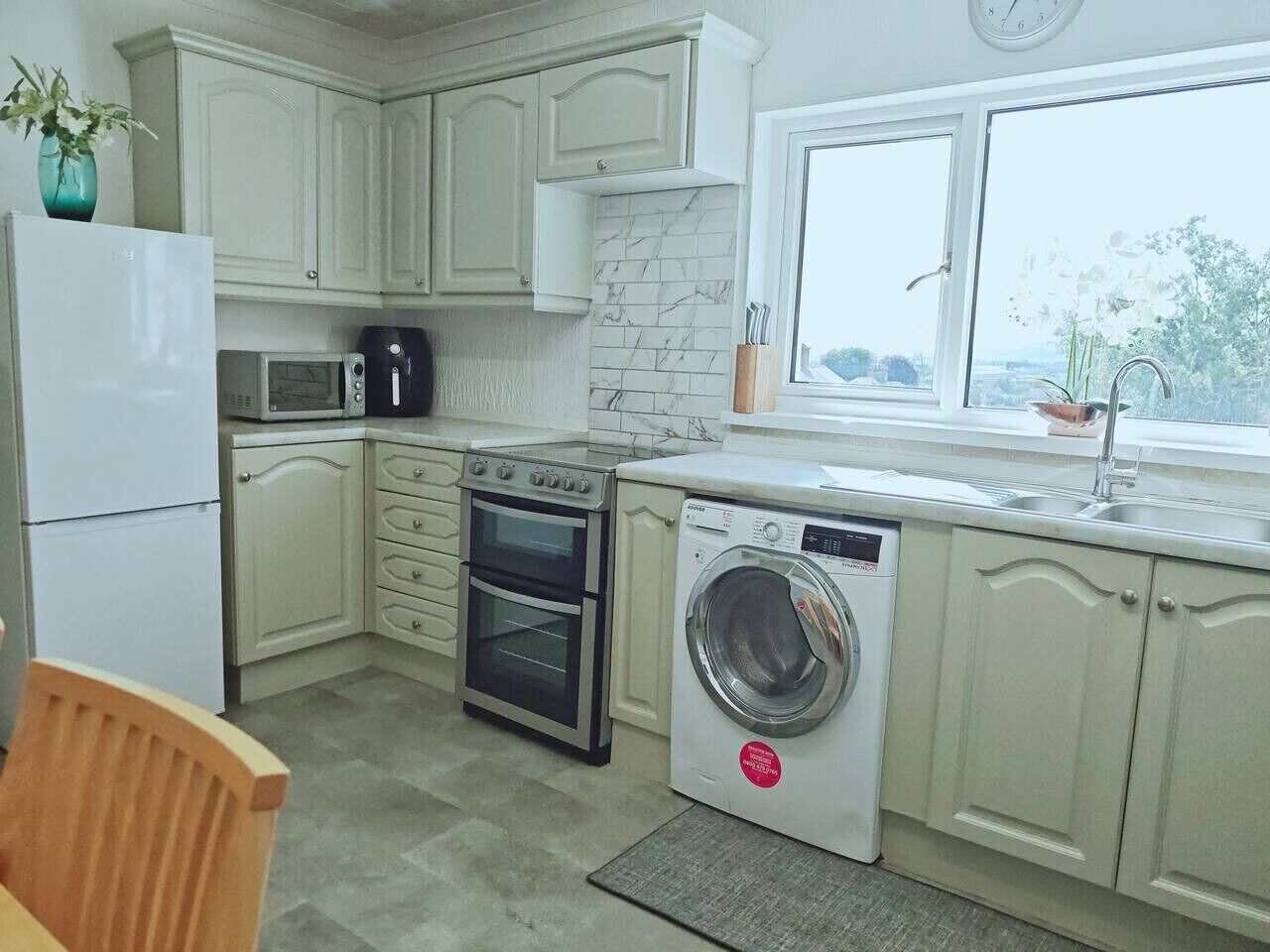 Une cuisine compacte avec des meubles blancs, un four à micro-ondes, un four traditionnel et un lave-linge.