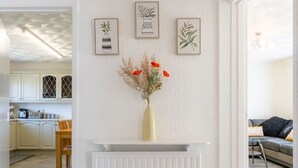 A modern interior with a white radiator, a vase with dried flowers, and framed botanical illustrations on the wall. - Family and pet-friendly flat near beach and countryside (Baglan)