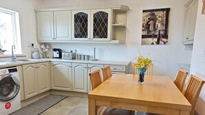 A compact kitchen with a dining area, a washing machine, and a dining table with chairs. - Family and pet-friendly flat near beach and countryside (Baglan)
