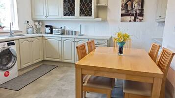 A compact kitchen with a dining area, a washing machine, and a dining table with chairs.