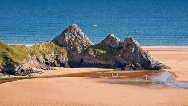 Paisaje costero con afloramientos rocosos y una playa de arena.