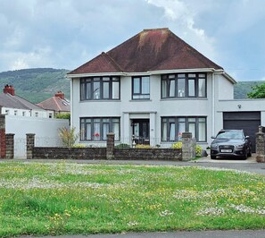 A two-story house with a garage, a driveway, and a lawn with flowers.