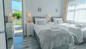 Un dormitorio moderno con dos camas, un ventanal con cortinas translúcidas y vistas al exterior.