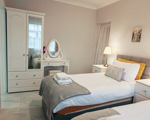 A bedroom with a bed, nightstands, a dresser, and a mirror.