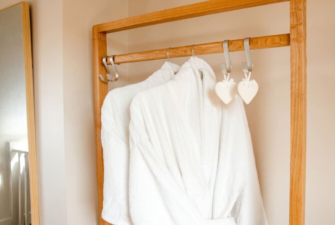 A wooden rack with white robes and heart-shaped tags.