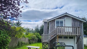 A wooden cabin with a balcony, a picnic table, and a customer parking sign. - Cozy, Quite, Private Loft, Near Ocean, 
Center of Haida Gwaii (Port Clements) (Port Clements)