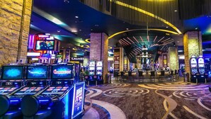 A casino with multiple slot machines and a carpeted floor with a circular pattern. - Cana Rock Star Condo Hotel (Punta Cana)