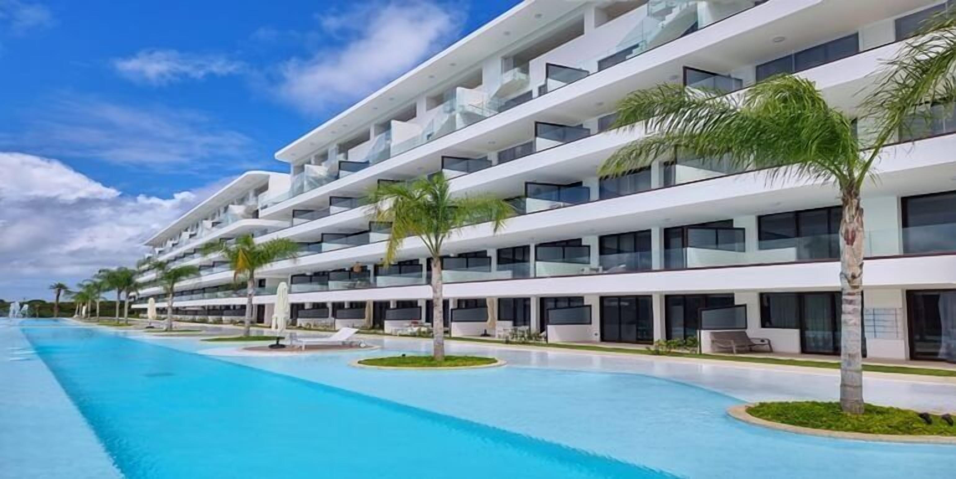 Un hôtel moderne doté de nombreux balcons, d’une piscine et de palmiers.