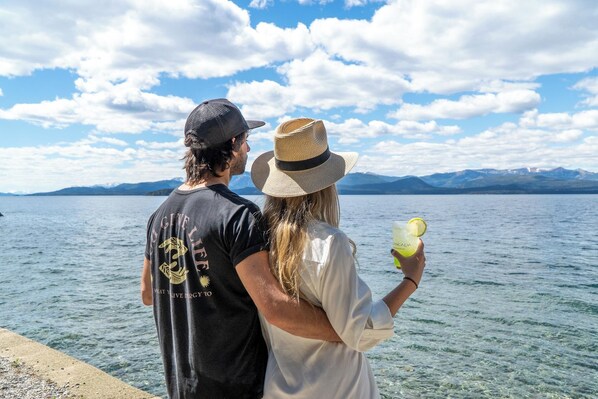 A couple standing by a lake with mountains in the background.