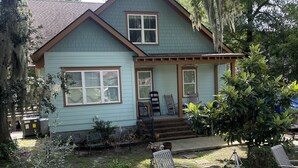 A two-story house with a porch, a garden with hydrangeas, and outdoor furniture.