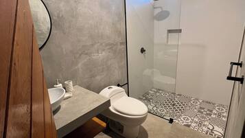 A modern bathroom with a toilet, sink, and shower.
