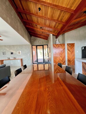 Un salón de conferencias con una mesa y sillas de madera, una pared de piedra y vistas al exterior.