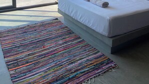 Quarto com uma cama grande, um tapete colorido e vista para o mar.