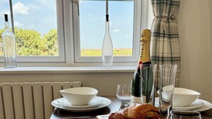 A dining table with white plates, bowls, glasses, and a bottle of champagne. - Four Counties Cottages, Collyweston (Collyweston)