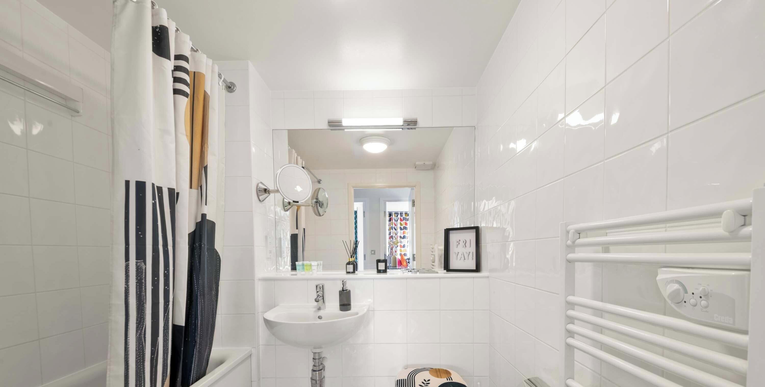 Un baño con lavamanos blanco, espejo y cortina de ducha.