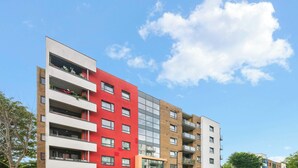 Un immeuble résidentiel à plusieurs étages, doté de balcons, de grandes fenêtres et surplombant un ciel dégagé.
