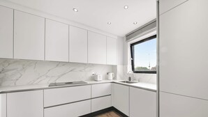Une cuisine moderne avec des meubles blancs, un plan de travail en marbre et une fenêtre offrant une belle vue.
