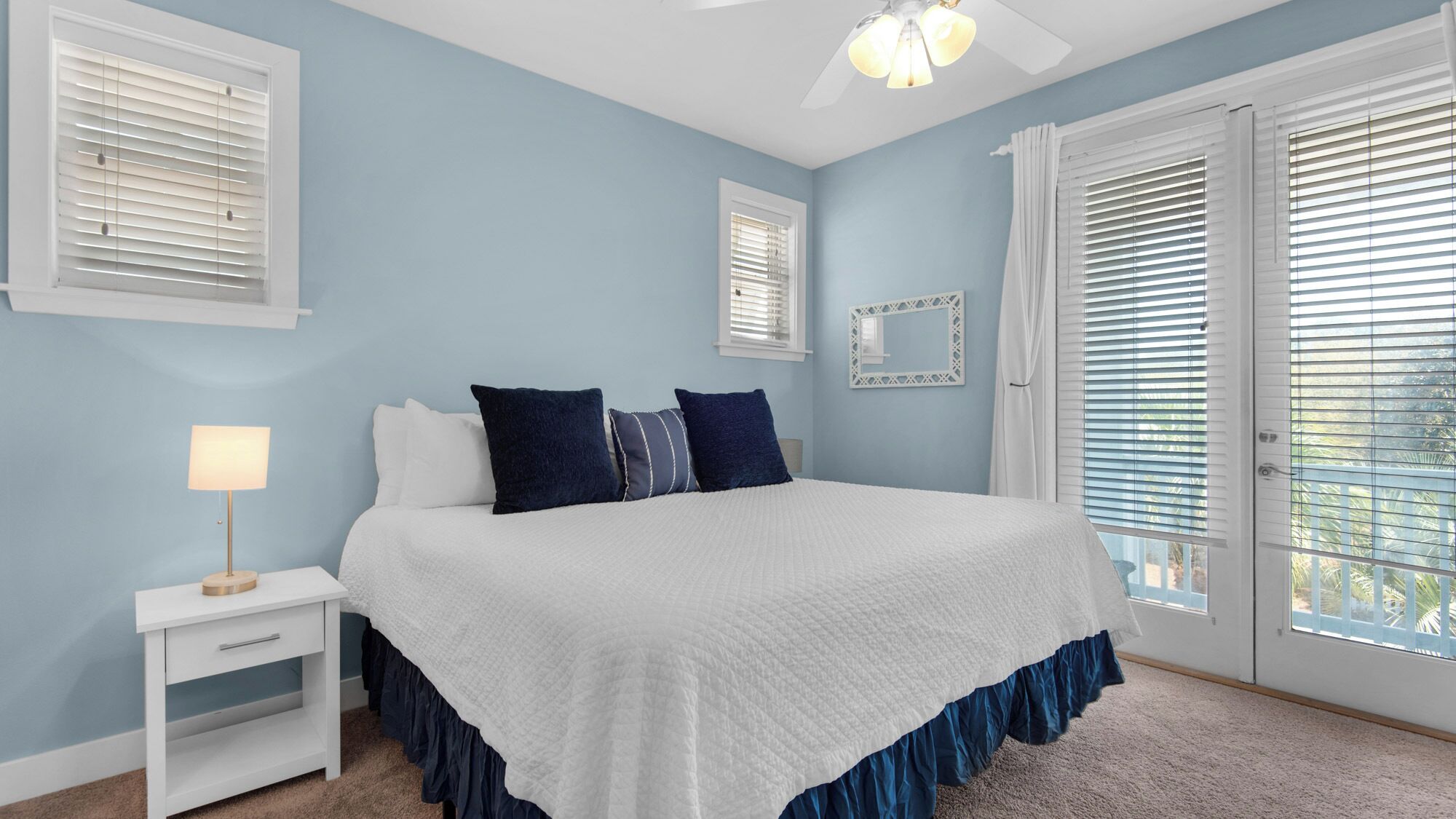 A bedroom with a bed, a nightstand, a lamp, and a ceiling fan.