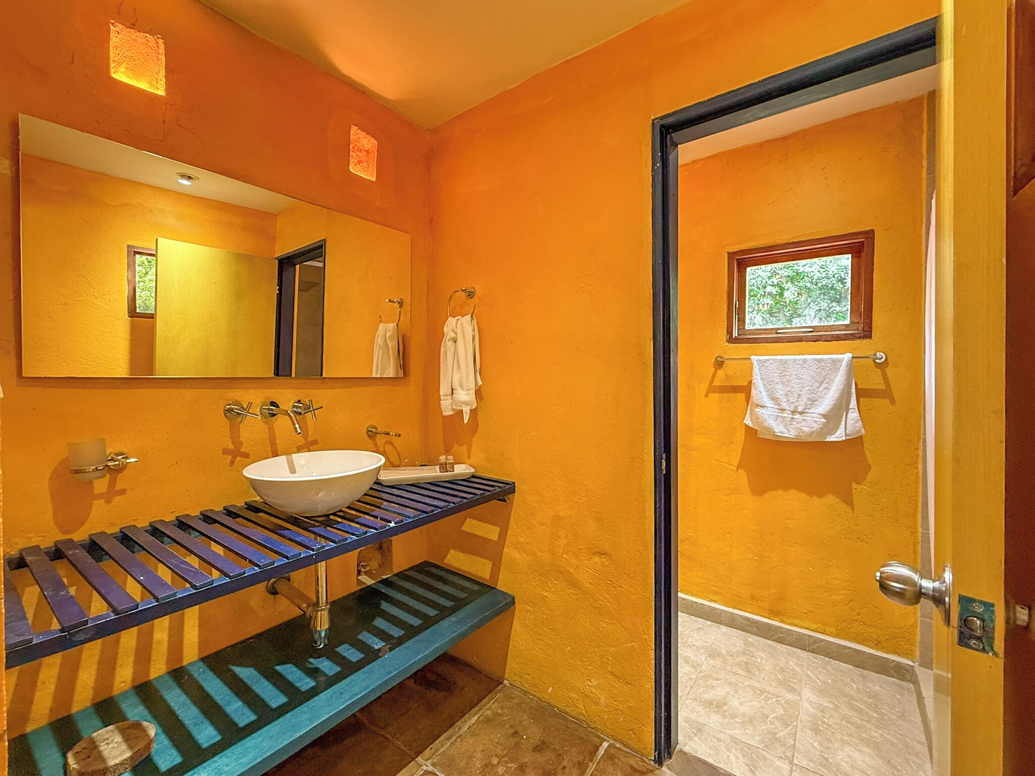 Un baño con un espejo grande, un lavabo y un perchero para toallas.