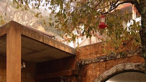 Un pati rústic amb un arc de pedra, una porta de fusta i una petita bassa.