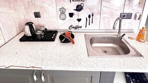 A kitchen with white cabinets, a granite countertop, and a sink. There are kitchen utensils and a coffee maker on the counter. - Taksim The Capital Center Hotel (Istanbul)