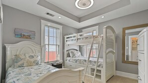 A bedroom with bunk beds, a single bed, a dresser, and a window with blinds.