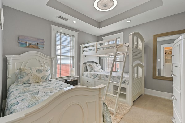 A bedroom with bunk beds, a single bed, a dresser, and a window with blinds.