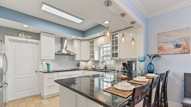 A modern kitchen with white cabinetry, a large island, and pendant lighting.