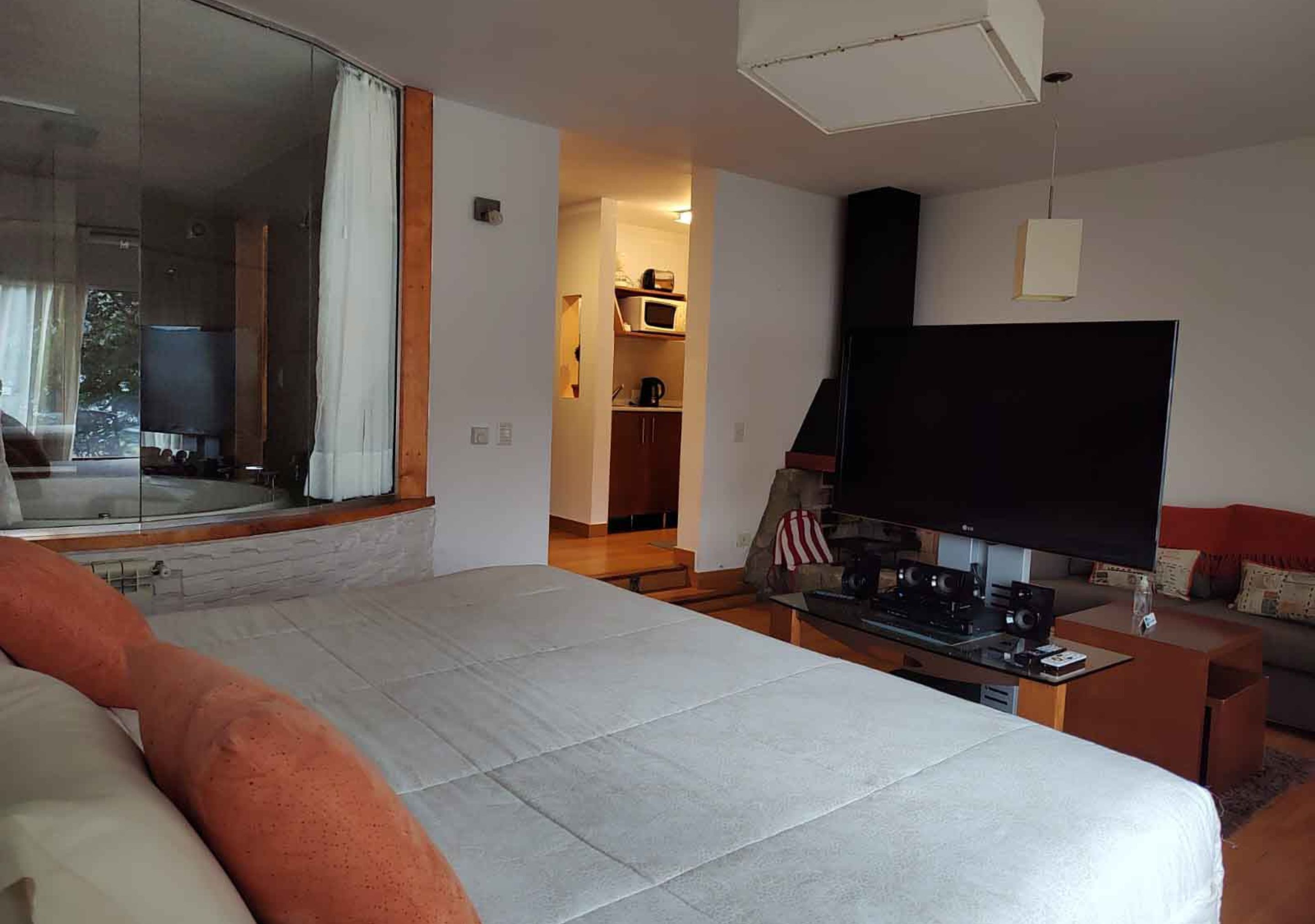 A modern hotel room with a large bed, a flat-screen TV, a coffee table, and a sofa.