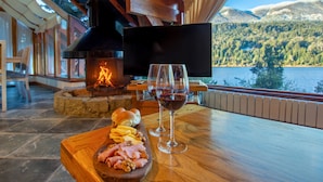 Una mesa de madera con una chimenea, un televisor y vistas panorámicas a un lago.