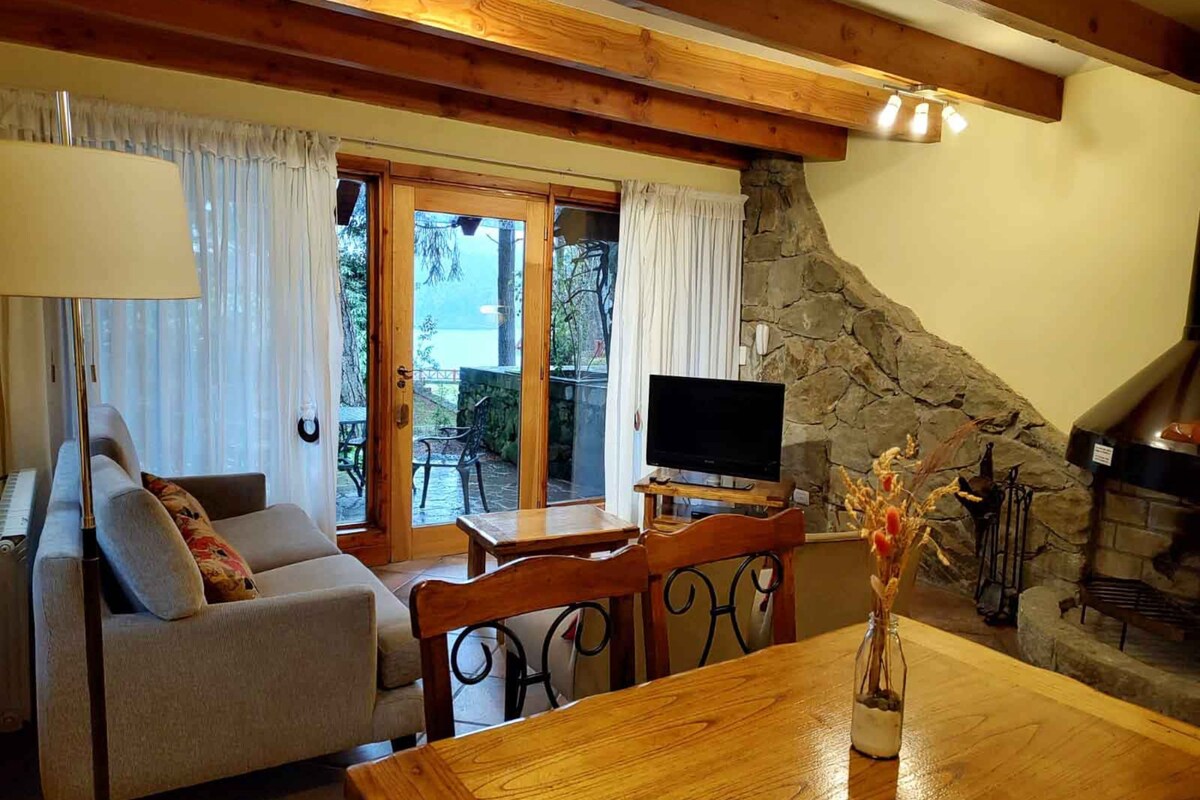 Uma sala de estar aconchegante com sofá, televisão e lareira de pedra.
