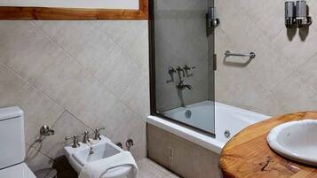 Un baño moderno con ducha envuelta en vidrio, tocador de madera y lavamanos blanco.