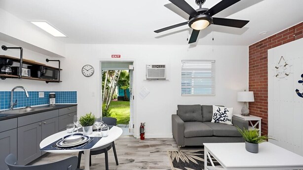 A modern kitchen with a dining area, a ceiling fan, and a view of the outdoors. - Luna Beach House (Hollywood)